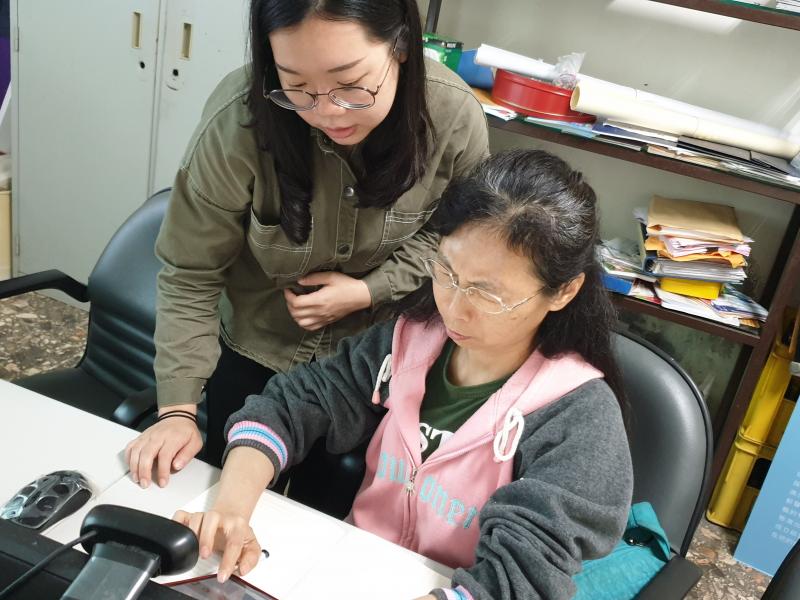 講師指導另一位將手機放在桌上的學員使用應用程式。