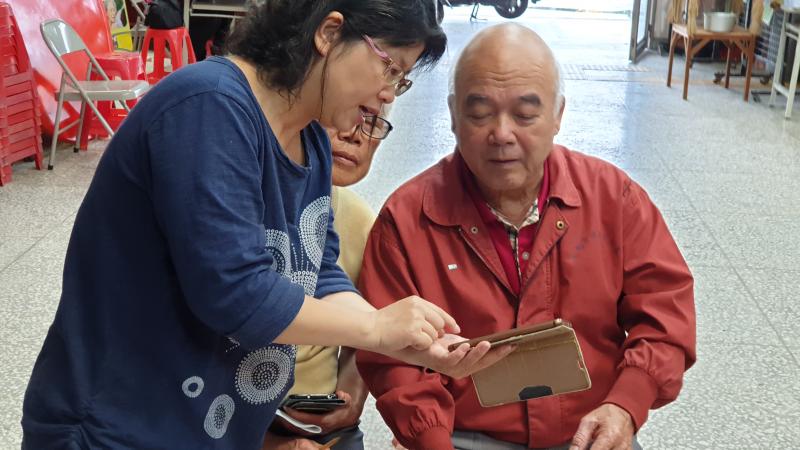 一位女性學員正在向長輩說明應用程式功能。