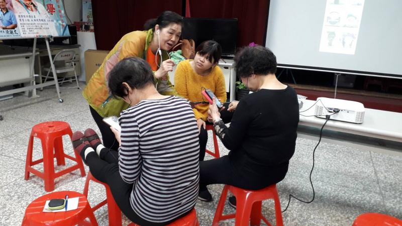 長輩學員們正帶著耳機，低著頭專心在自己手機上。