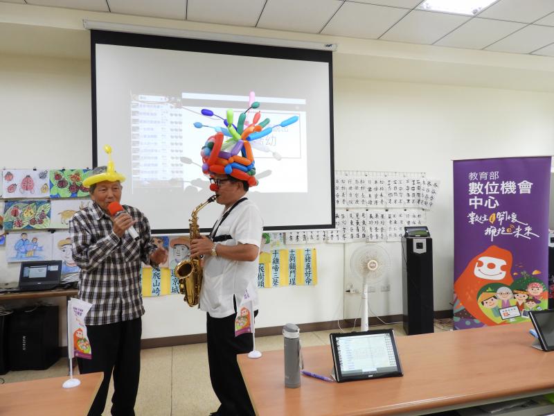 講師手拿著薩克斯風位學員伴奏，讓學員在台上高歌一曲。