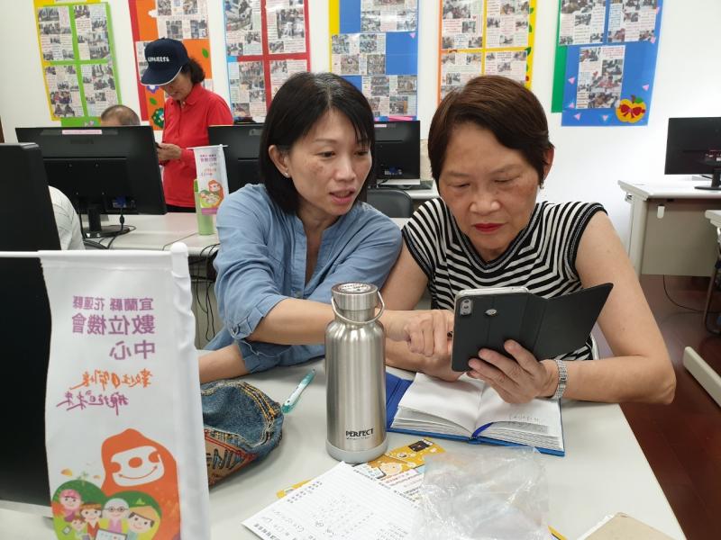 兩位學員彼此交流討論智慧型手機的使用方式。