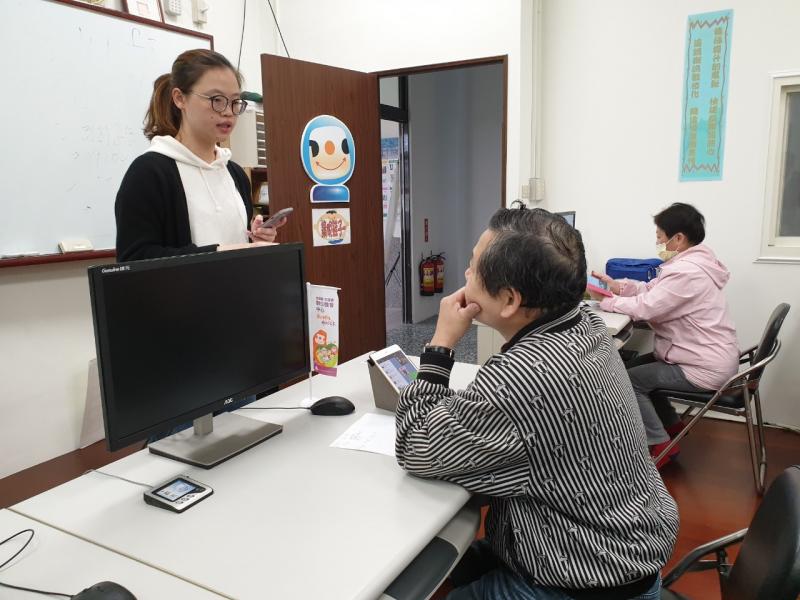 講師站在一位學員的面前講課。