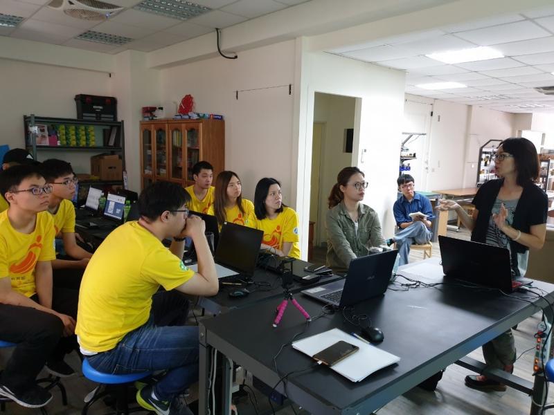 資訊志工正在討論要製作的項目主題，有人甚至將雙手放在桌上並且爆出握拳。