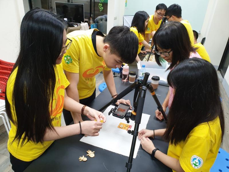 志工同學將藉由雷射雕刻的物件擺放與桌面上，經過調整拍攝成影片素材。