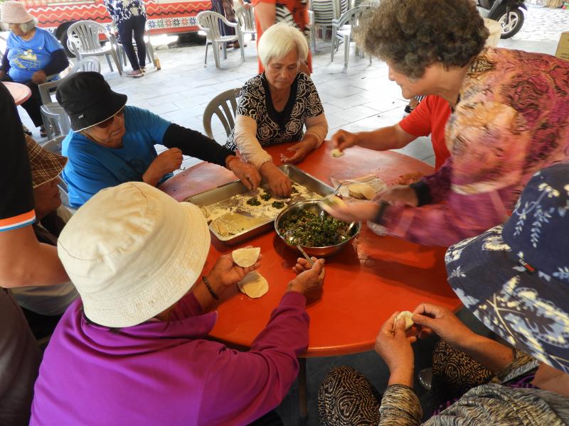 平板拍照的長者，跟煮菜的長者說，趕快換手，你們也要練習平板