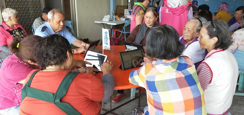 大家為坐在桌字旁像是開會的樣子，但實際上大家只是在盯著自己的平板電腦。