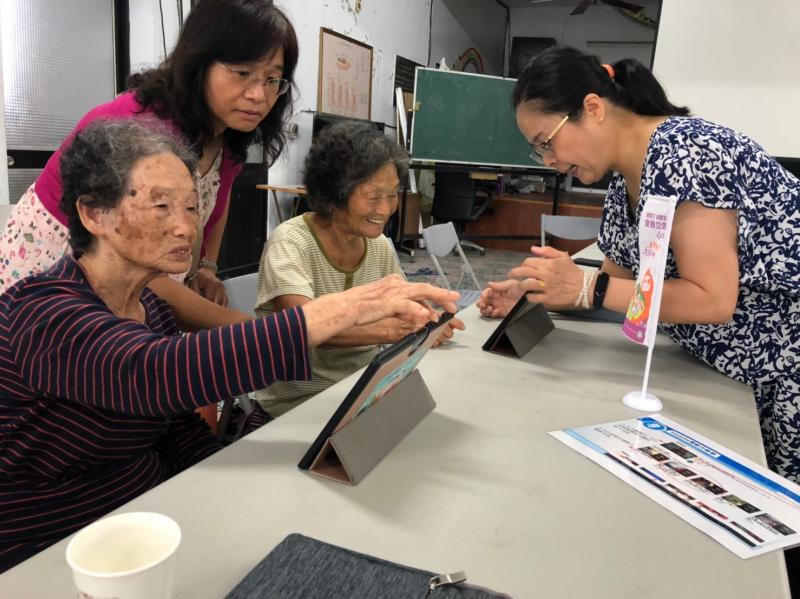 老師與志工一起引導學員操作平板電腦