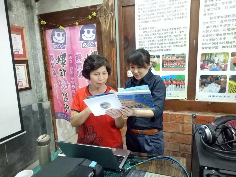 老師與學員手上持有著一本有關壯為歷史的書籍，共同討論繪本書內容，了解社區牽罟文化。