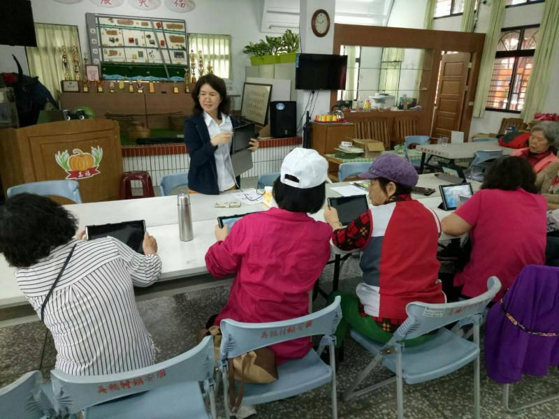 講師在長桌前詢問學員是否有不了解之處，兩三位學員不時將投靠過去看隔壁的平板電腦。