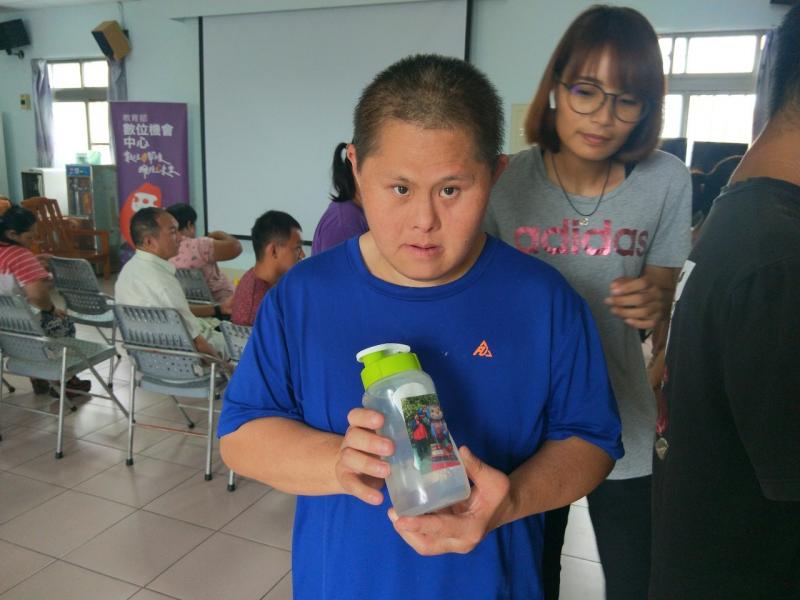 一位小朋友不同於其他人，將圖片熱轉印為貼紙，黏在自己的水瓶上面。