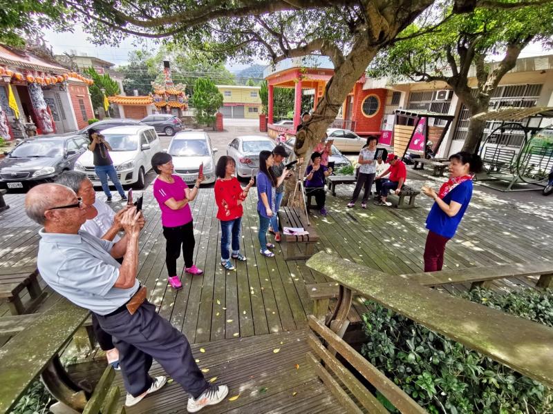 學員們手持手機和平板，在戶外對著直播主秋香準備開始練習直播