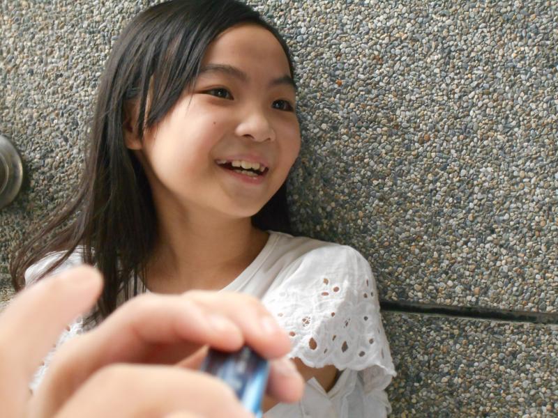 模特兒身穿白色蕾絲，長髮自然散落臉頰兩旁，帶有露出牙齒的微笑。