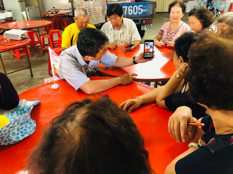 講師坐在學員們的面前,以左手拿著手機示範LINE的視訊鏡頭。