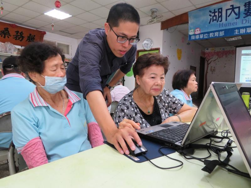 助教協助示範電腦操作，學員認真聽著解說內容