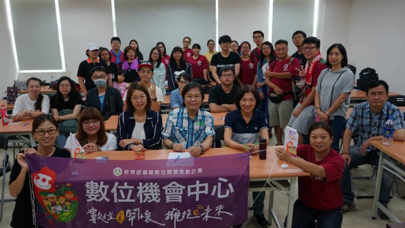 DOC的輔導員與駐點人員將數位機會中心的布條舉在桌子前方，將大家聚集在一起拍了一張大合照。