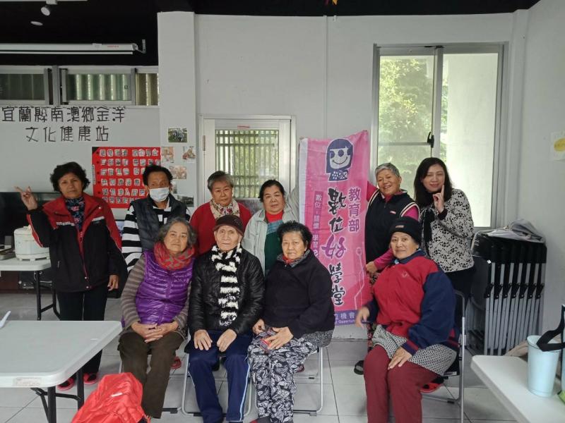 長輩們站在數位機會中心-數位好學堂的旗幟旁邊，臉上帶著笑容拍了一張合照。