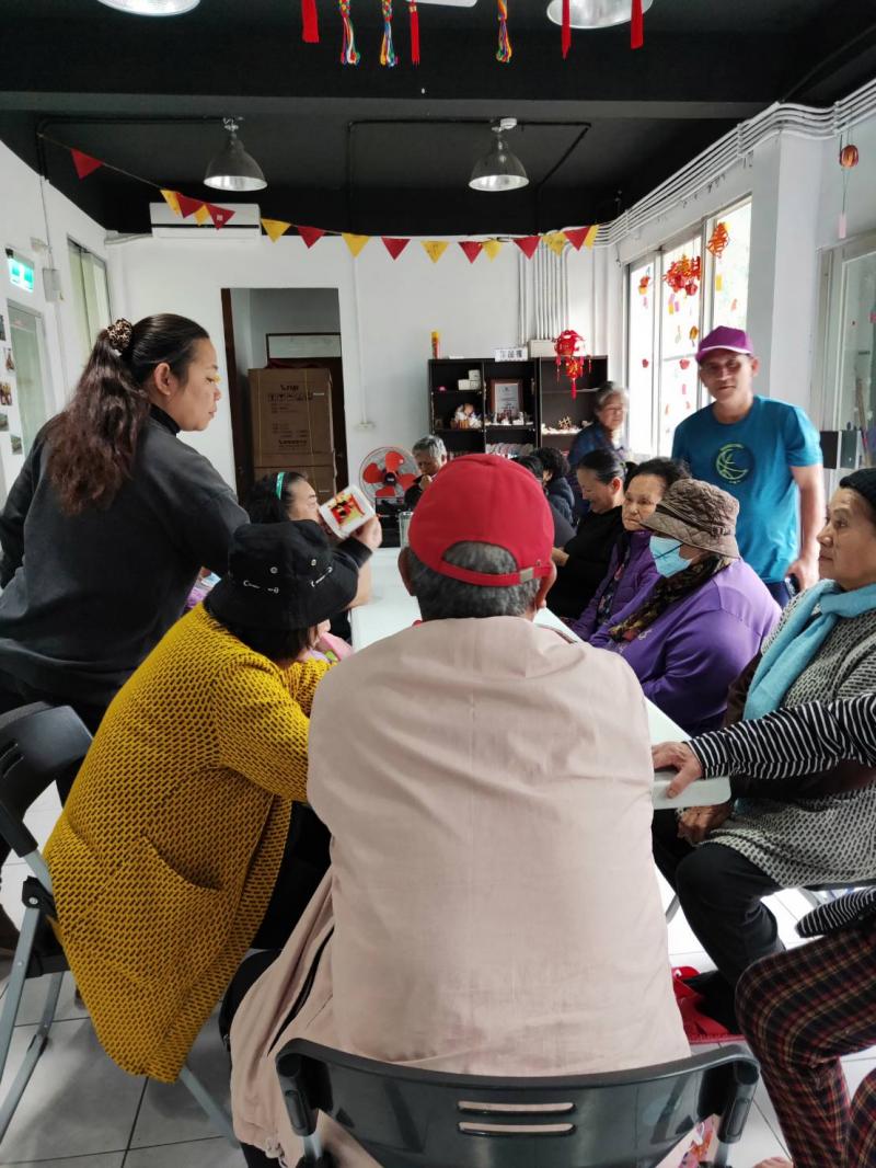 學員們圍坐在長桌旁，其中一位將已經熱轉印的馬克杯拿起做為展示。