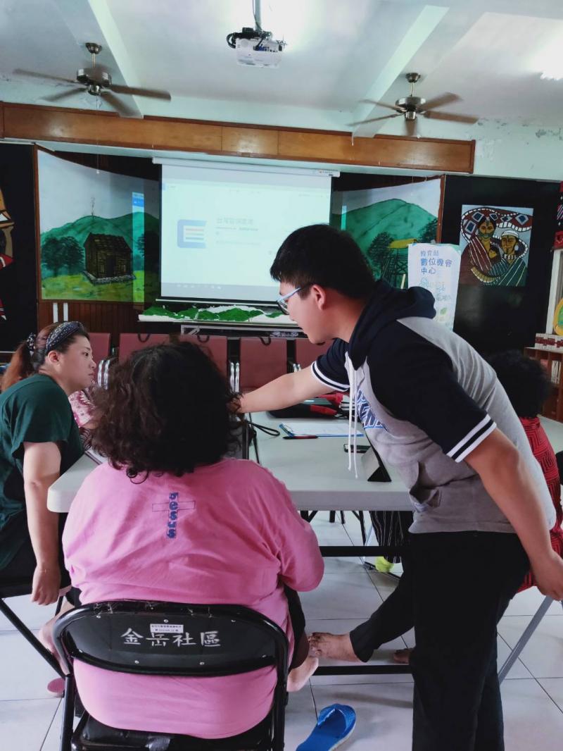 老師站在長輩的右邊，用手指示平板上應該點擊的地方，協助長輩完成設定問題。