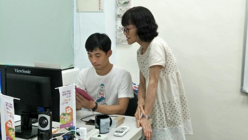 講師坐在自己的座位上，前來詢問問題的學員將手機交付給講師，並且詢問問題。