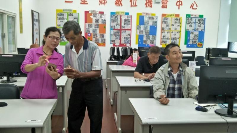 一位長輩學員請教其他學員智慧型手機的操作方式。