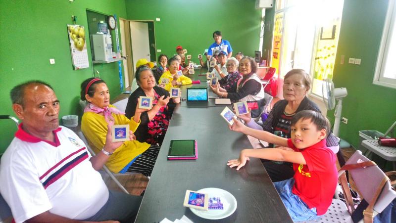 學員們將自己所做好的熱轉印作品拿在手上，坐在長桌前拍了一張大合照。