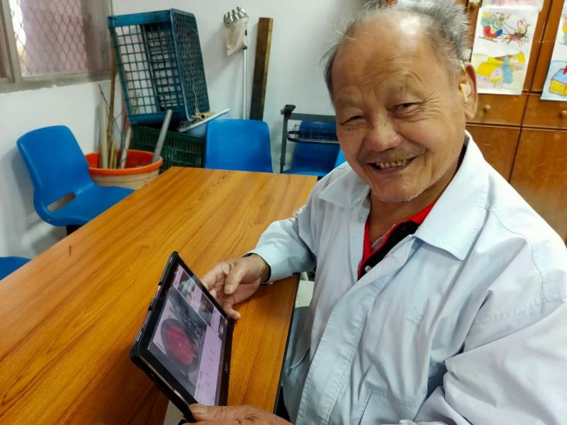 阿公在平板電腦上玩youtube聽音樂，很開心