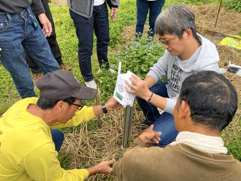學員圍繞在講師身邊，仔細觀看講師裝機