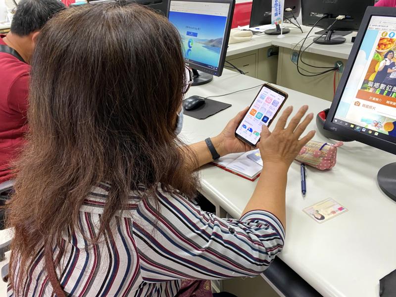 學員手拿智慧型手機，用身分證件及金融卡進行認證及綁定