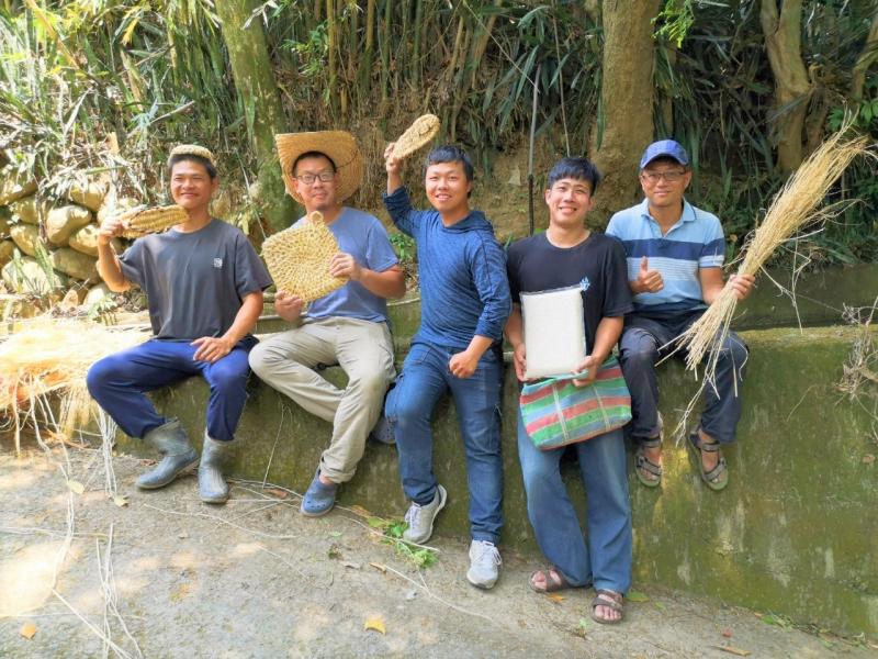 青農們在水圳旁拿著草編織品燦笑合照