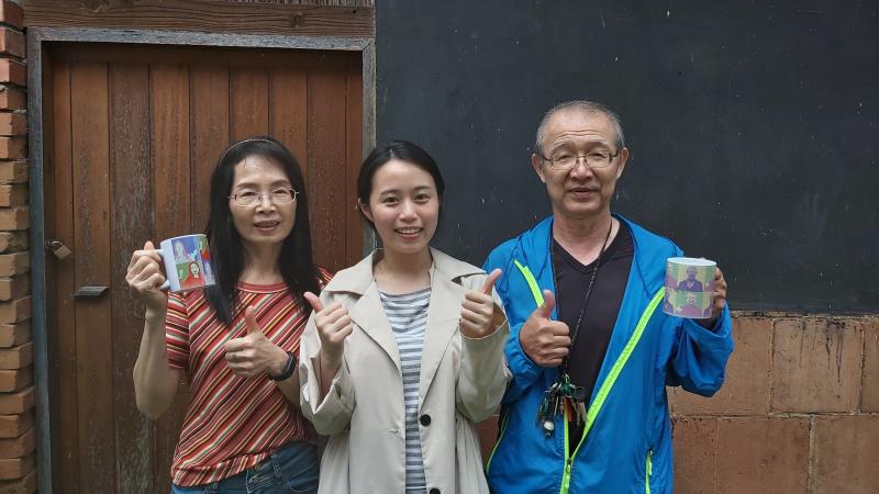 學員拿著自己製作的馬克杯與講師合影。