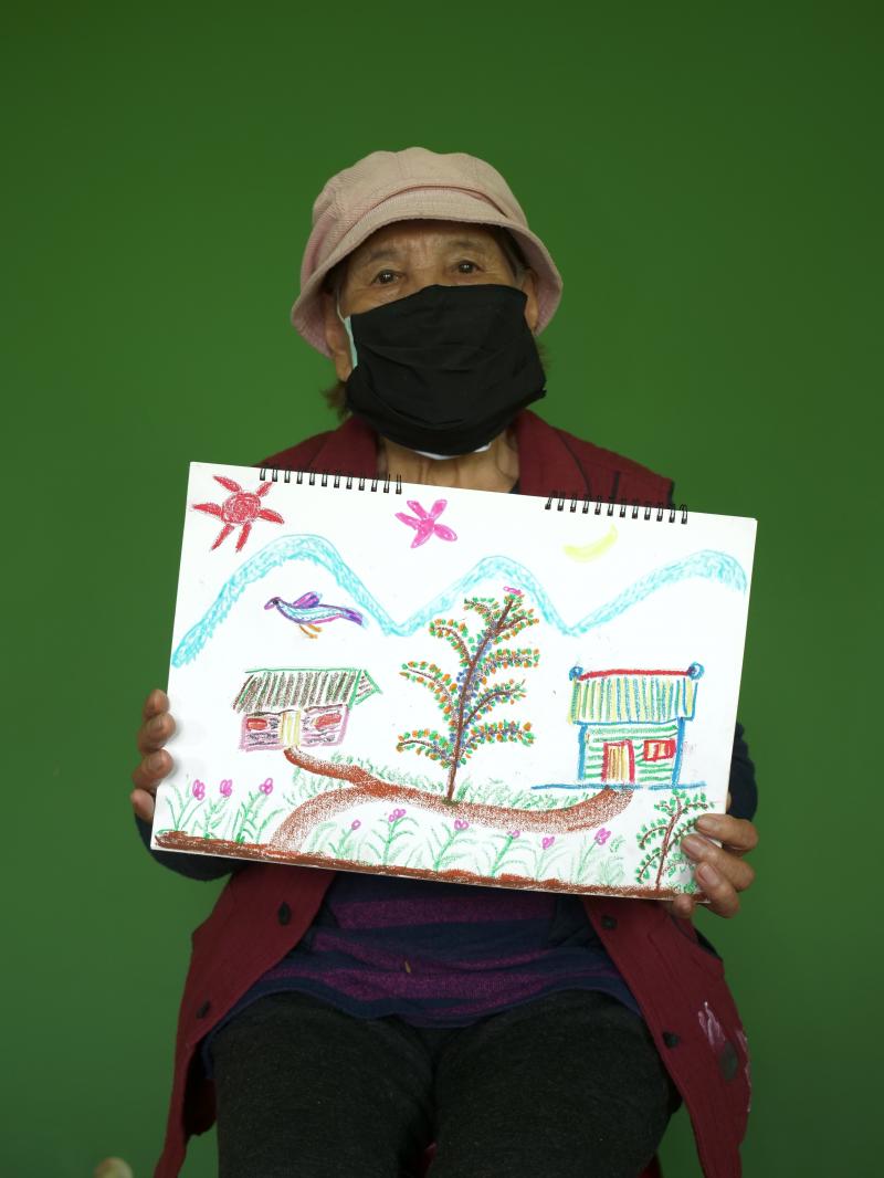 圖中的阿嬤，展現自己的畫作，將自己的生活分享出去