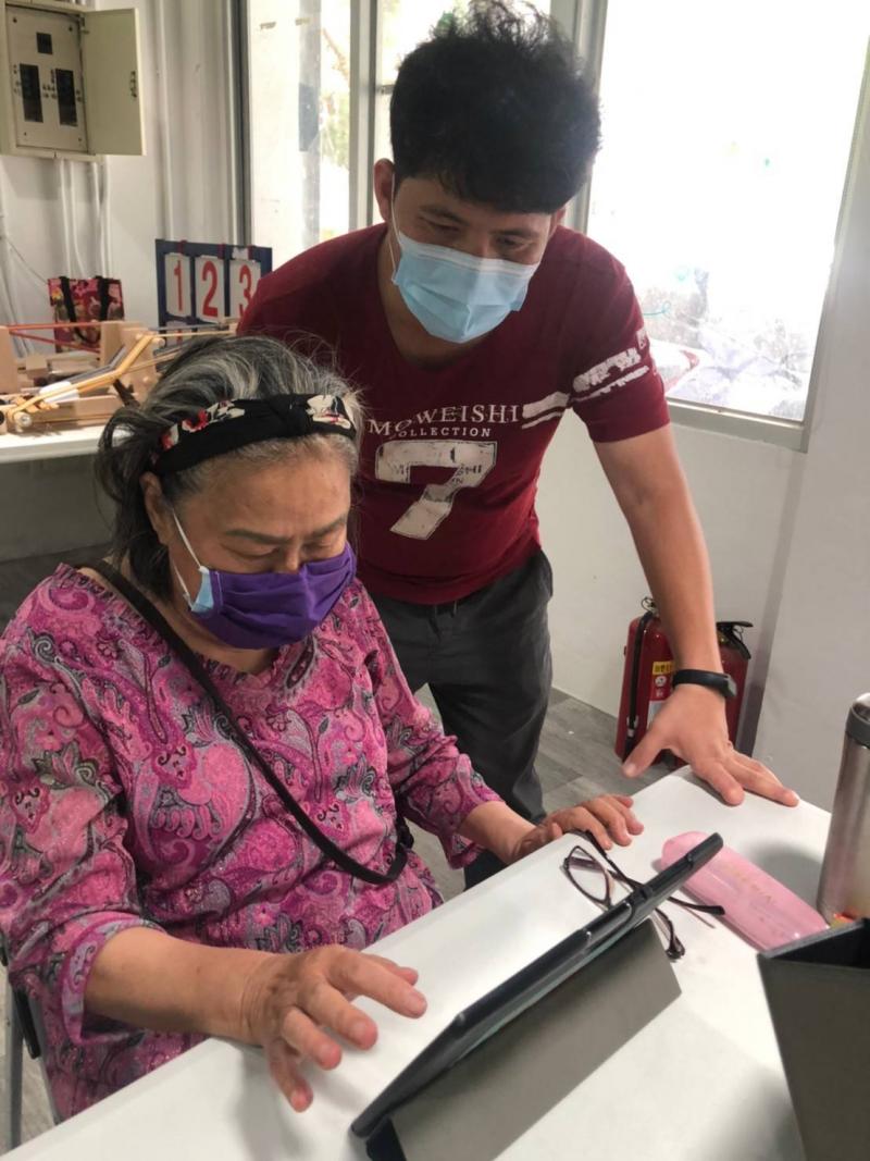 講師細心的教導圖中的阿嬤，阿嬤也好認真的學習呀~