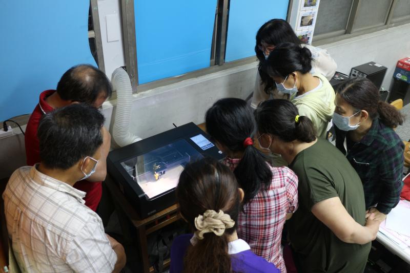 看著機器左右滑動著，飄出一陣陣木頭燒焦味一件件手機架作品產出