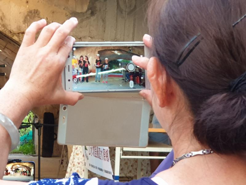 一位女性拿著手機在幫台上的人拍照