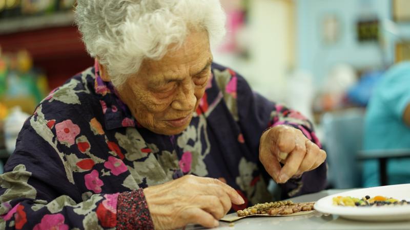 信義LINE貼圖一起來課程，高齡80幾歲奶奶專心的將一顆顆豆子排出圖案。
