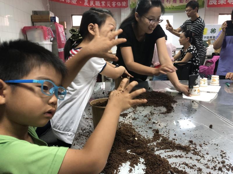 小朋友玩培養土，家長在旁紀錄中。