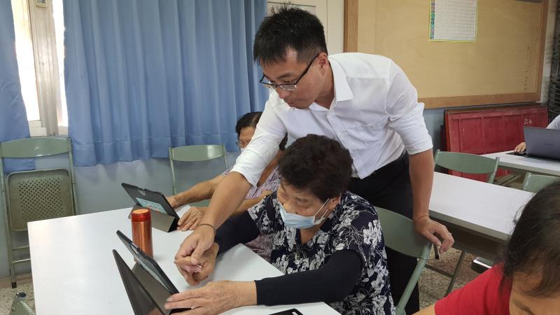 學員第一次使用平板，講師楊禮仁手把手引導學員如何用手指觸摸平板。