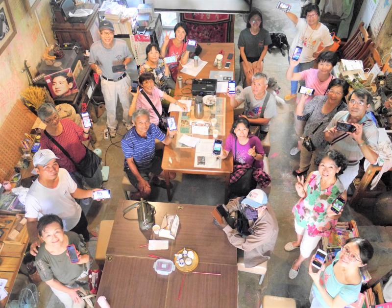 學員們在書店內用手機展示自己的早安圖，一起仰臉大合照