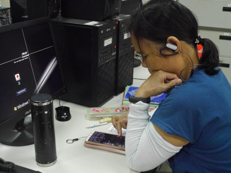 一位女學員戴著耳機用手機專心剪輯