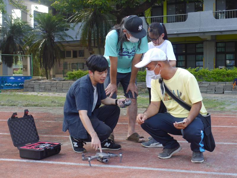 講師在操場上指導旁邊的男學員空拍機操作
