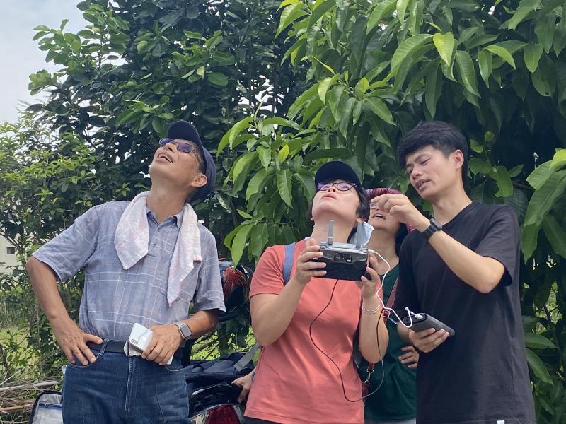 學員們和講師一起用手機操作空拍機,望向天空