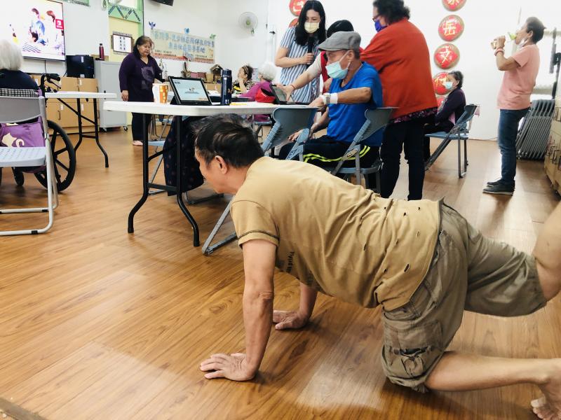 長輩很認真的跟著平板下載的健身app一起做運動