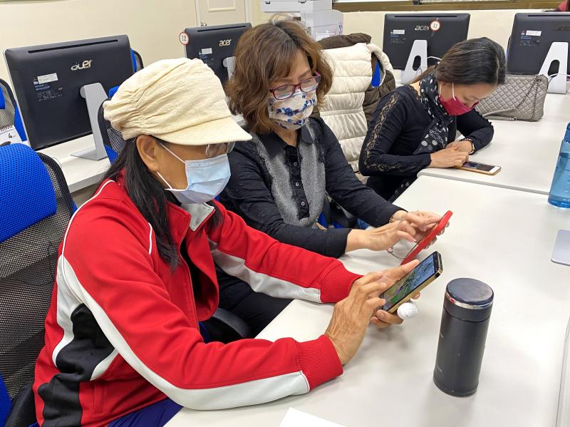 學員手拿智慧型手機，練習運用手機修圖軟體