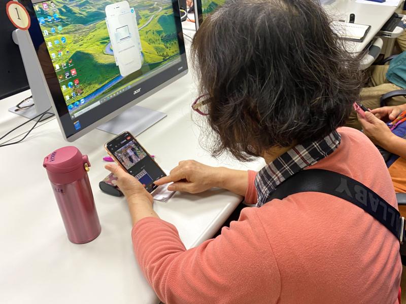 學員手拿智慧型手機，進行影片剪輯