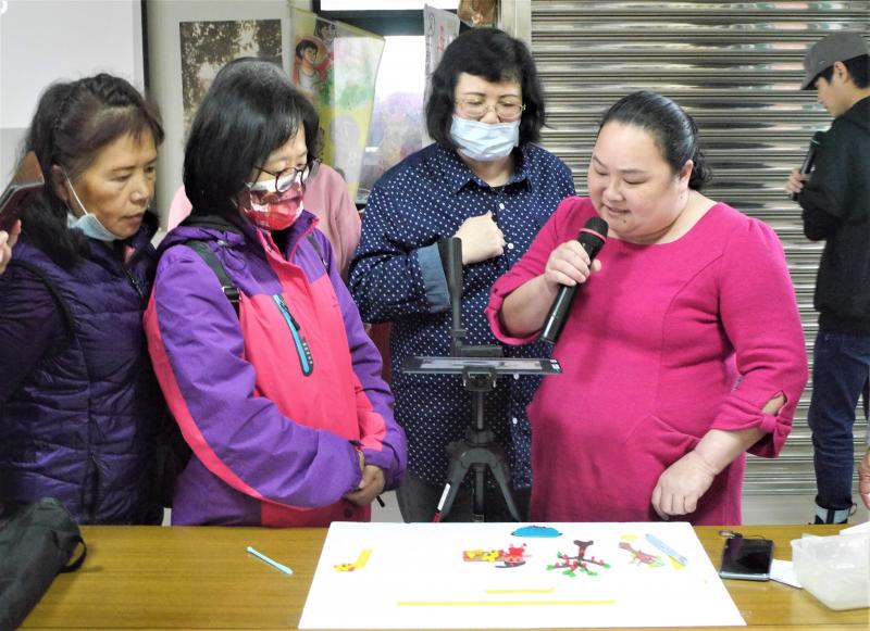 學員持麥克風在桌前對著平板進行配音