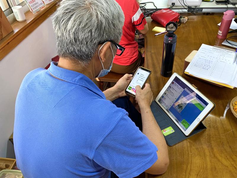 學員一邊使用手機下載修圖軟體，一邊用平板找尋想修整的照片