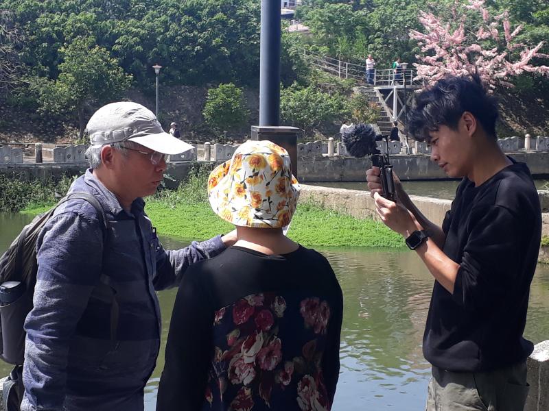 老師拍攝同學表演的畫面,一個角色向另一個角色出示照片