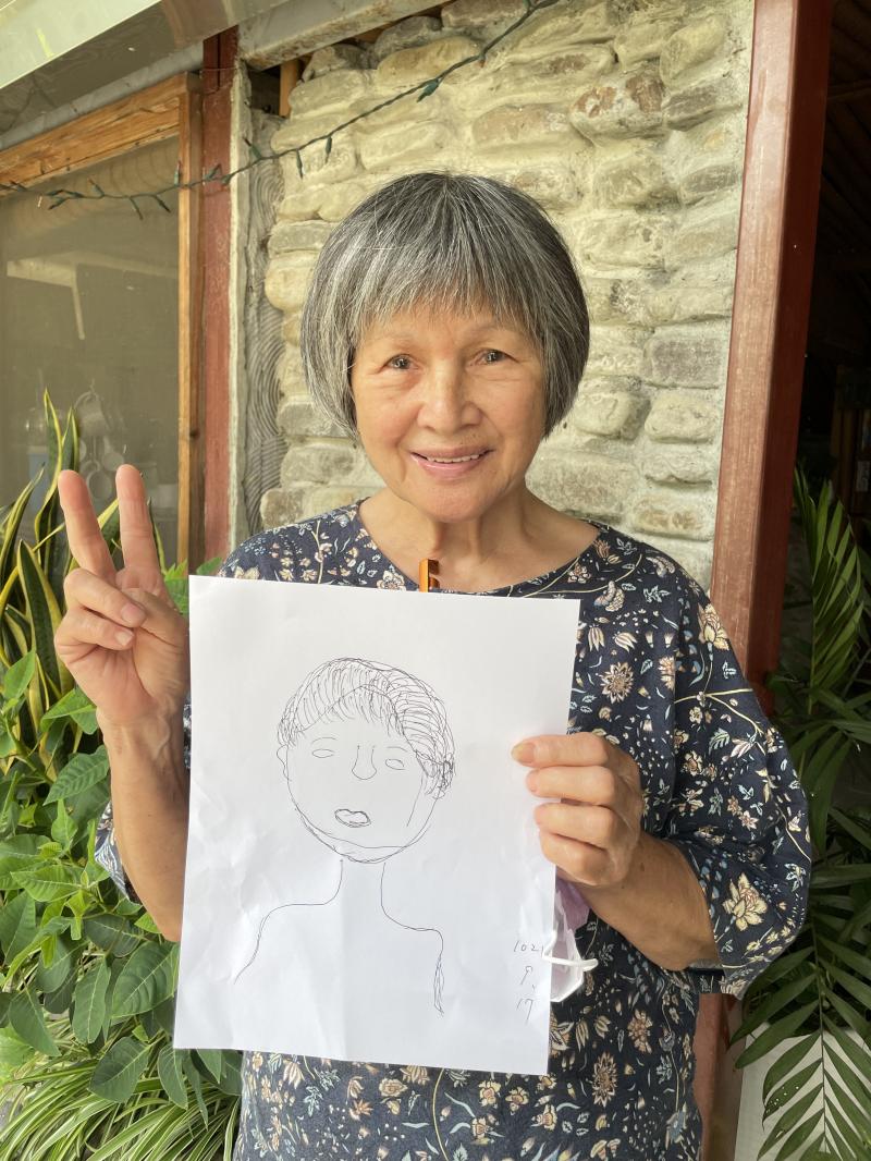 學員與自己的畫像作品合照，對自己的創作感到很滿意。