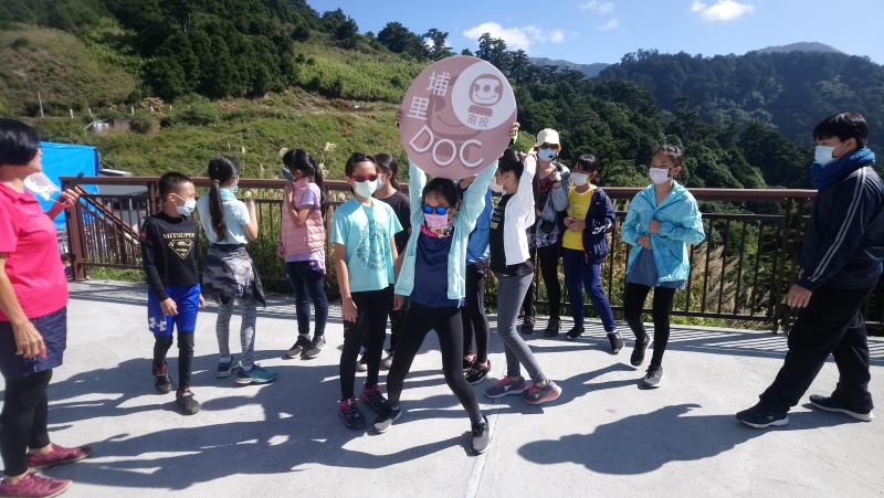 溪南國小新科學生會長在暗空公園高舉著「埔里DOC」的珍珠板