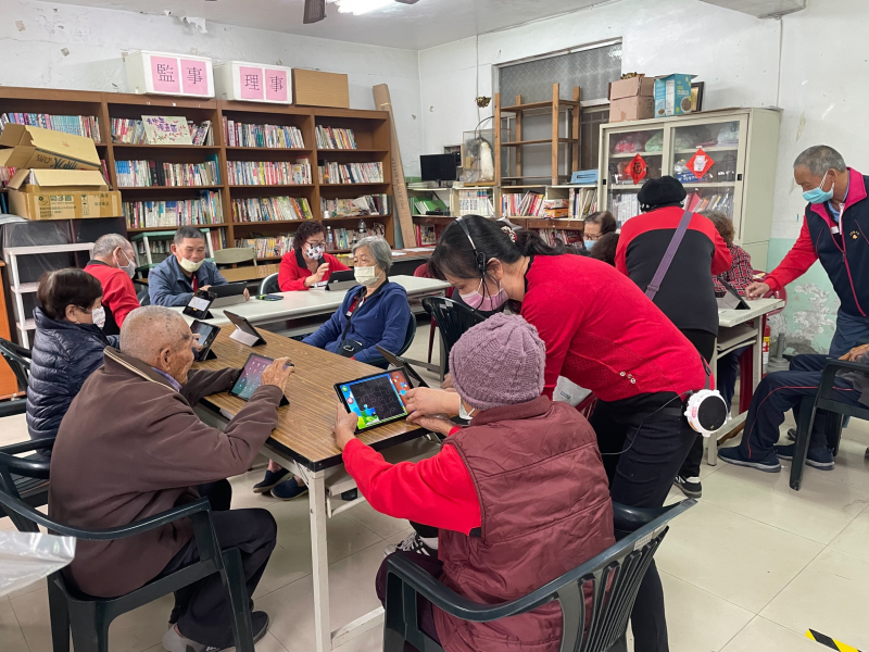 圖片是講師正在教長輩們如何使用平板裡面的音樂小遊戲